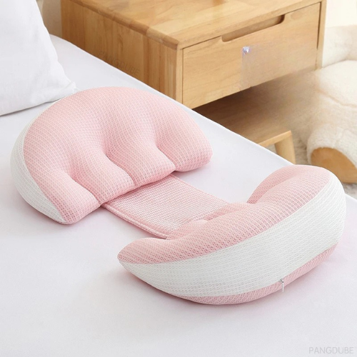 כרית תמיכה ורודה ולבנה בצורת U מונחת על מיטה ליד שידת עץ – כוללת רצועת חיבור במרכז, אידיאלית לתמיכה בבטן של נשים בהריון או לשינה נוחה יותר.

